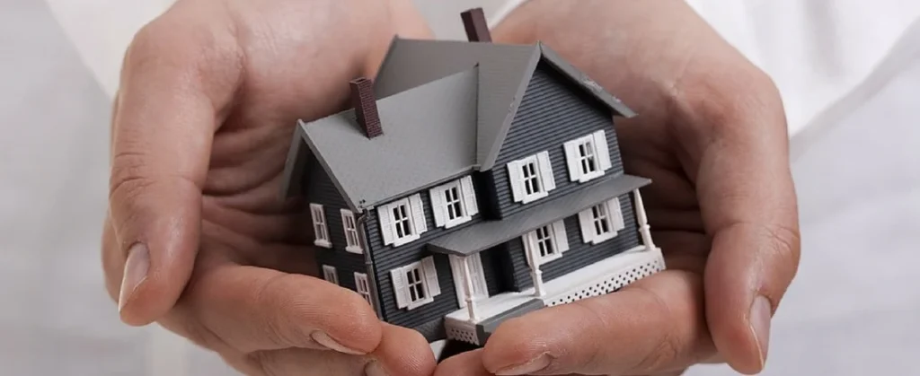 First-time home buyer grants can help make homeownership more affordable, illustrated by hands holding a model house representing financial assistance and support for new buyers.